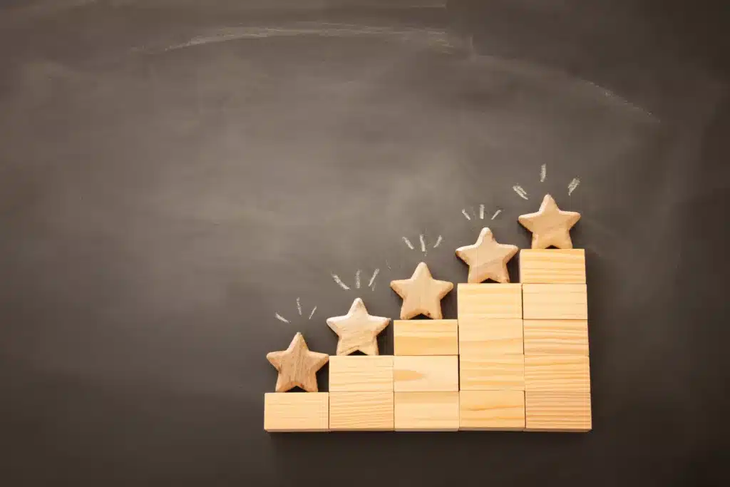 Five wooden stars stacked on top of each other on a blackboard.