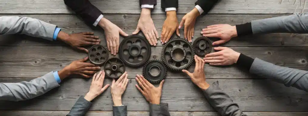 A group of business people holding gears in a circle.