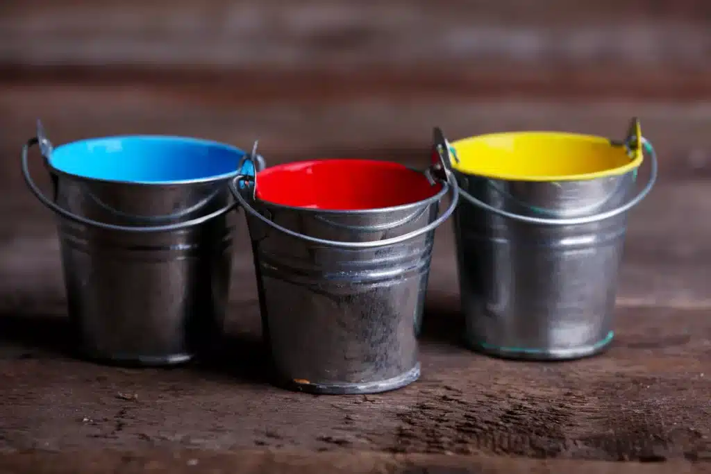 Three metal buckets on a wooden table.