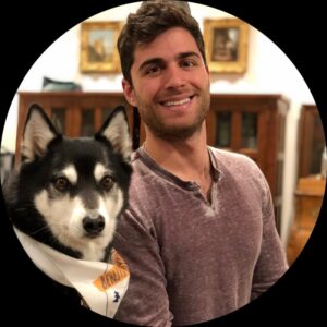 A man with a husky dog in a living room, discussing the highlights of PagerDuty Summit 2022 and the innovative features of Chronosphere.