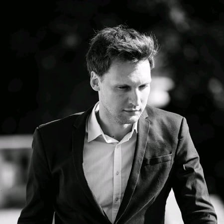 A man in a suit and collared shirt contemplates the real world in a black and white photo.