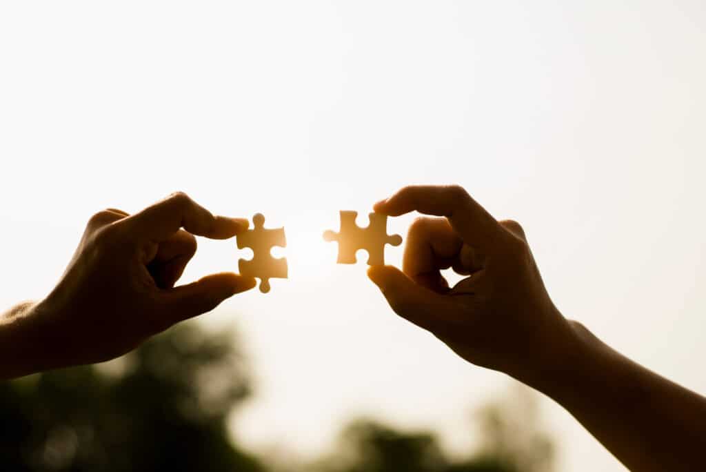 Two hands holding a puzzle piece in the sun, symbolizing the future of promQL compatible observability.