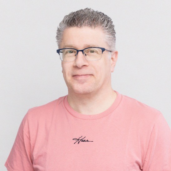 A man wearing glasses and a pink t-shirt with full cycle observability technology.