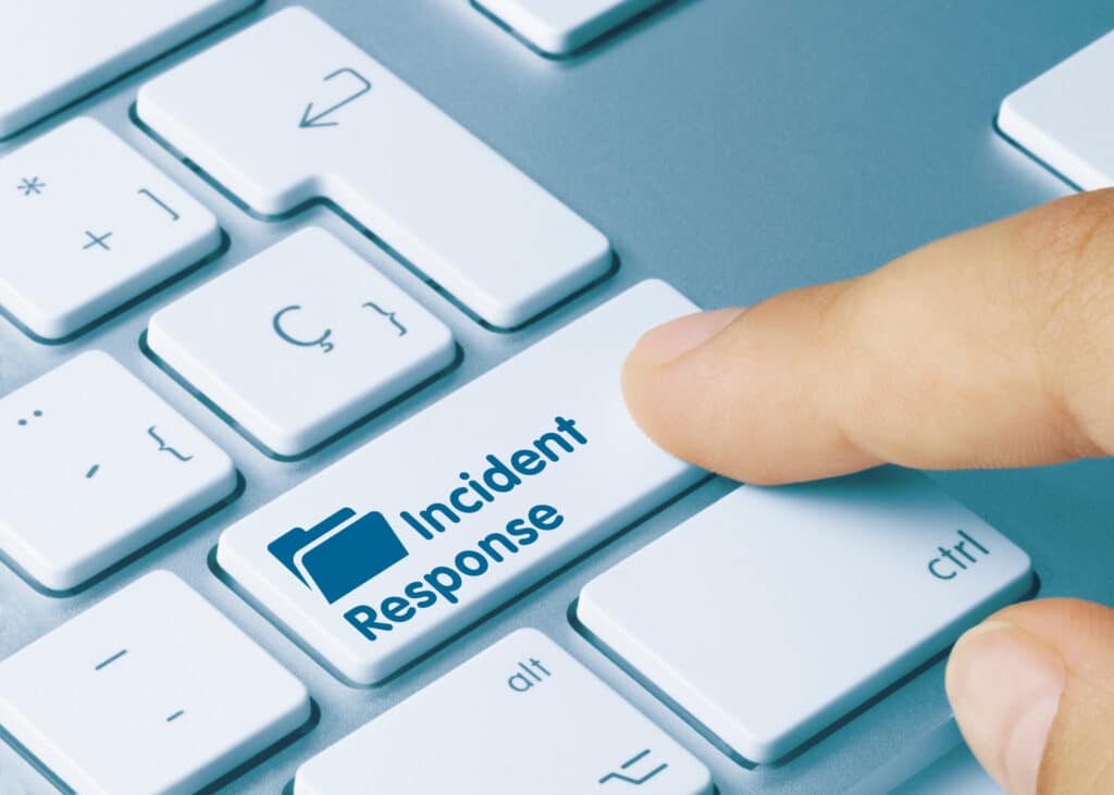 A person working at an energy company is pressing a button on a keyboard that says incident response.