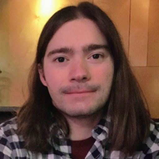 A man with long hair and a plaid shirt attending a webinar on observability costs in cloud native orgs.