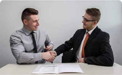 Two men shaking hands at a desk, showcasing their professional features and establishing a solid framework for collaboration.