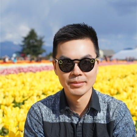 A man wearing sunglasses in front of a field of tulips.