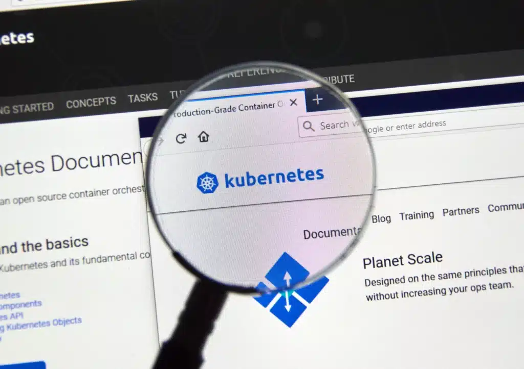 The observability of Kubernetes is enhanced as a magnifying glass reveals insights on a computer screen.
