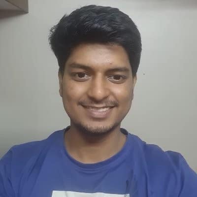 Sharad Regoti, with short dark hair and a beard, smiles at the camera while wearing a blue t-shirt.