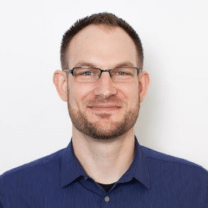 A person with short hair, glasses, and a beard.